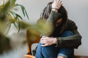 An image of a woman holding her head and looking down, appearing to be anxious.