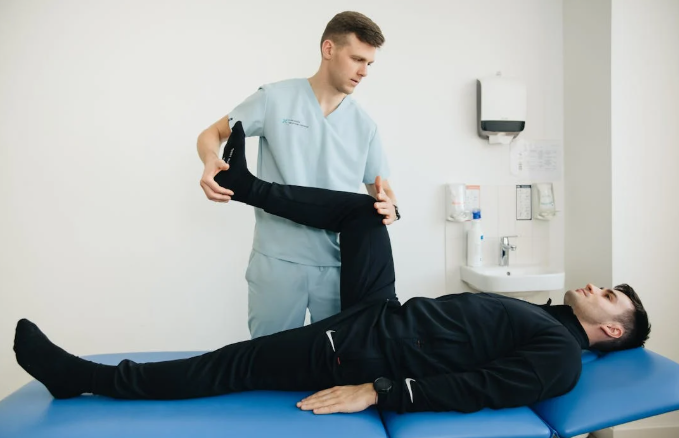 physiotherapist assisting a patient with leg exercises during rehabilitation